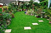 SMALL GARDEN WITH FLOWER BORDERS,  STEPPING STONES ON LAWN AND CONTAINERS