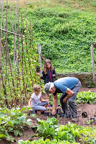 Grandfather_and_his_granddaughters_gardening_in_a_vegetable_garden_in_summer_Moselle_France
