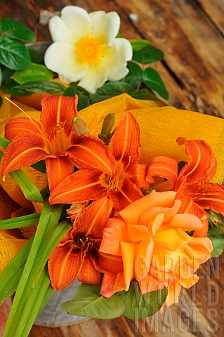 Orange_Daylily_Hemerocallis_fulva_and_Rose_Rosa_sp_in_a_bouquet_on_a_wooden_table
