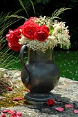Bouquet of flowers outdoors, Red Roses (Rosa sp) and Elder flowers ( Sambucus sp), in a pewter pot