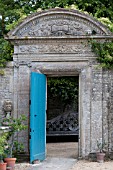 STONE ARCHWAY WITH BLUE DOOR IN FORMAL FRENCH GARDEN, CHATEAU DE BRECY
