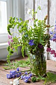 WOODLAND FERNS IN JAR WITH VINCA, BLUEBELLS AND DICENTRA