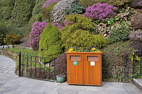 SPRING_FLOWERS_DECORATE_A_RUBBISH_BIN_AGAINST_A_BACKGROUND_OF_HEATHERS_AND_CONIFERS_AT_BUTCHART_GARD