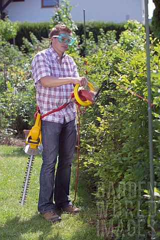 PERSON_CUTTING_PRUNING_HEDGES_WITH_ELECTRIC_TRIMMER