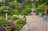A plant lovers cottage garden borders of herbaceous perennials grey metal containers with shaped box hedging and holly sun-dial and gravel paths at Coley Cottage (NGS) Little Haywood, Staffordshire