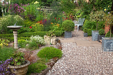A_plant_lovers_cottage_garden_borders_of_herbaceous_perennials_grey_metal_containers_with_shaped_box