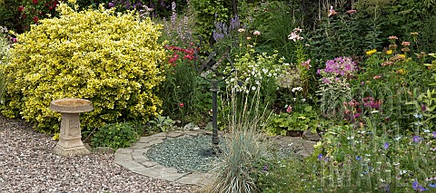Border_of_summer_flowering_herbaceous_perennials_with_sundial_set_in_gravel_area