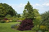 Views of open countryside from garden with borders of herbaceous perennials