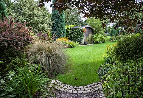 Garden_view_from_gravel_path_to_wooden_garden_shed_sweeping_borders