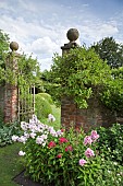 Brick wall and pillars to open iron gate, lawns and borders of herbaceous perennials