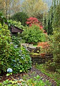 Colouful garden with a wide variety of mature trees and shrubs, seating and table