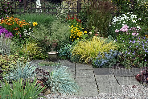 Gravel_and_paved_area_with_borders_of_summer_flowering_herbaceous_perennials_and_ornamental_grasses