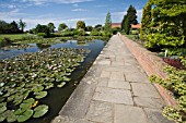 THE TOP POND AT RHS GARDEN,  HYDE HALL WITH A PATH AND LOW WALL RUNNING ALONG SIDE THE WATER.
