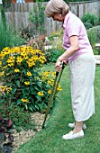 LADY TRIMMING LAWN EDGE WITH LONG HANDLED FLAT EDGING SHEARS.MODEL RELEASED
